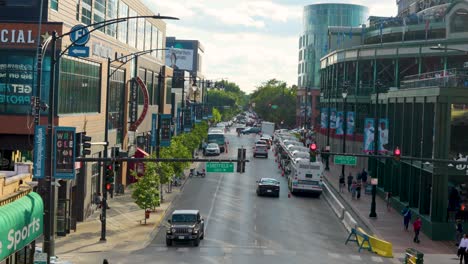 Una-Bulliciosa-Calle-De-Chicago-Con-Una-Dinámica-Vida-Urbana,-Con-Vehículos,-Peatones,-Escaparates-Y-Edificios-Modernos-Bajo-Un-Cielo-Azul-Claro.