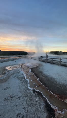 Vertikale-Ansicht,-Frau-Geht-Allein-Auf-Holzweg-Im-Yellowstone-Nationalpark-Zwischen-Heißen-Quellen-Und-Geysiren