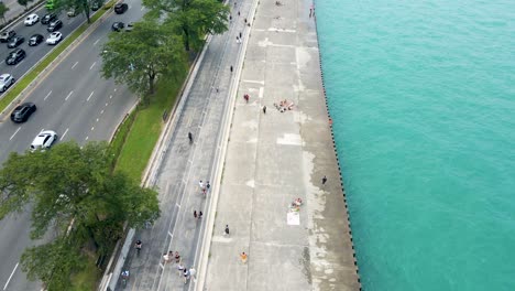 Aerial-drone-view-of-a-serene-lakeside-promenade-with-pedestrians-enjoying-a-leisurely-day-in-Chicago