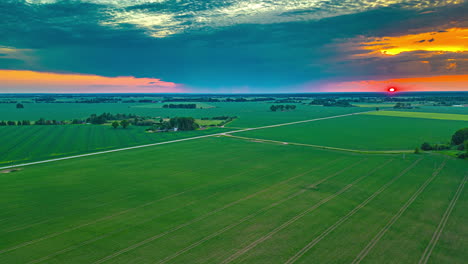 Dramatic-clouds-moving-over-rural-fields,-during-sunset---Aerial-Hyperlapse