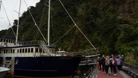 Panning-view-of-a-tourist-cruise-ships-at-the-terminal-in-Milford-Sound-Marina-on-a-cloudy-day