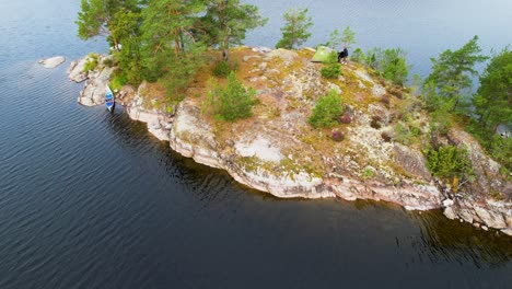 A-secluded-island-with-a-tent-and-canoe-in-sweden,-aerial-view