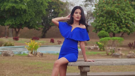 At-a-park-on-the-Caribbean-island-of-Trinidad,-a-girl-in-a-blue-dress-basks-in-the-sun