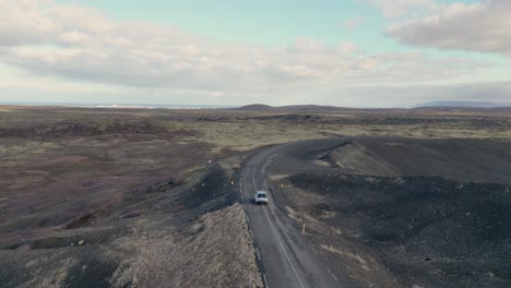 The-car-drives-through-an-endless-road-in-Icelandic-wilderness,-surrounded-by-volcanic-rock-and-soft-moss