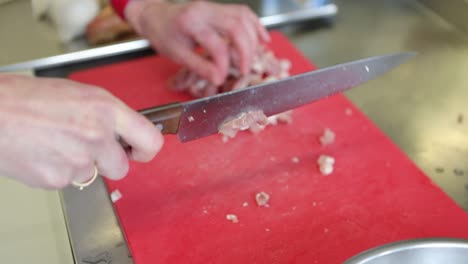 Chef-chopping-meat-on-a-red-cutting-board-with-a-knife