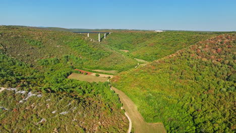 Aerial-flyover-a-valley,-dried-of-the-summer-sun,-approaching-a-bridge-in-Croatia