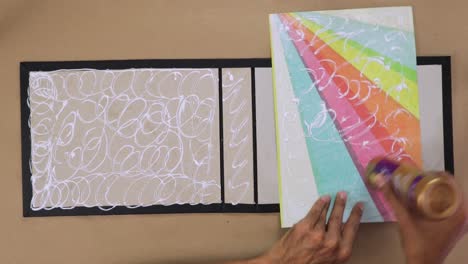 Hand-gluing-rainbow-colored-paper-to-a-scrapbook-cover-for-a-DIY-project,-close-up-view