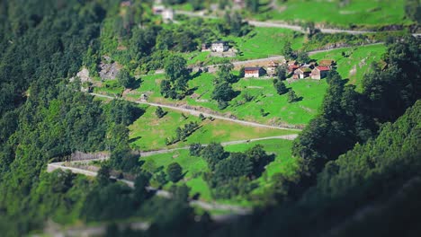 Scenic-aerial-shot-of-a-tranquil-village-along-the-coastline,-with-verdant-hills-and-a-winding-road