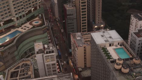 A-bustling-street-in-hong-kong-surrounded-by-tall-buildings-and-rooftops,-aerial-view