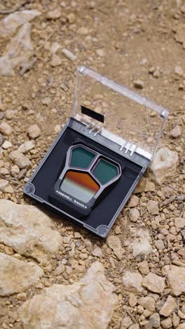 Vertical-shot-of-drone-nd-filter-in-open-plastic-case-on-rocky-surface