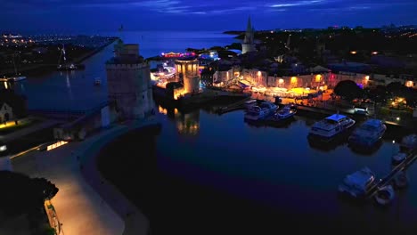 Old-port-of-La-Rochelle-with-Chain-and-Saint-Nicolas-towers-at-night,-France