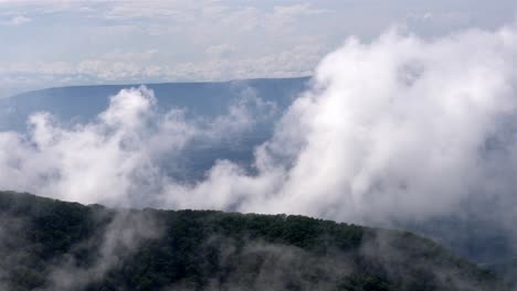 Handheld-footage-captures-mesmerizing-mountain-vista-as-clouds-slowly-drift-from-lower-left-to-upper-right,-enveloping-lush-forested-hills