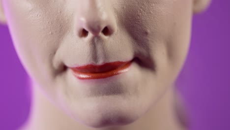 Close-Up-Of-Woman's-Face-and-Mouth-With-Red-Lipstick-On-Her-Lips-Against-Purple-Background,-Studio-Shot