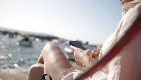 Vista-Recortada-De-Una-Mujer-Que-Usa-Un-Teléfono-Inteligente-En-La-Bahía-De-San-Pablo,-Malta