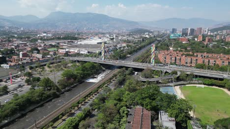 Sobrevuelo-De-Las-Concurridas-Calles-De-La-Ciudad-Para-Tender-Un-Puente-Sobre-El-Río-En-Medellín,-Colombia