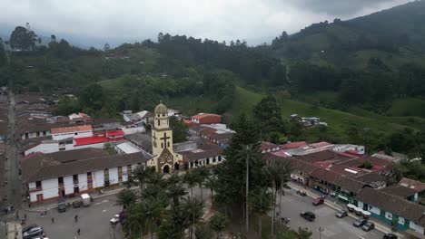 Aerial-flyover-Bolivar-Plaza-to-church-bell-tower-in-Salento,-Colombia