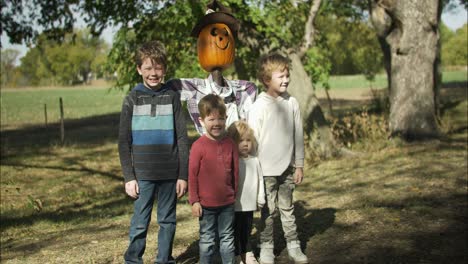 Happy-kids-with-pumpkin-scarecrow-at-halloween-pumpkin-patch