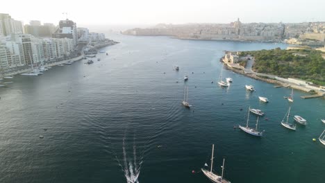 Boats-cruise-below-drone-at-sunrise-in-Malta