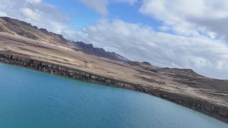 Islands-Geologische-Wunder-Werden-In-Dieser-Luftaufnahme-Eines-Kreisförmigen-Blaugrünen-Sees,-Umgeben-Von-Dunkelschwarzen-Felsformationen,-Voll-Zur-Schau-Gestellt