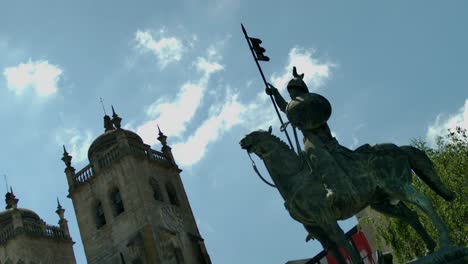 Eine-Statue-Mit-Einem-Mann-Auf-Einem-Pferd-Vor-Einem-Kirchturm-In-Porto