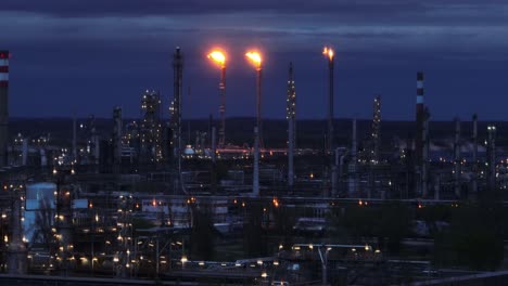 Dramatic-night-view-of-an-industrial-refinery-with-gas-flares-illuminating-the-dark-sky---aerial-drone-view