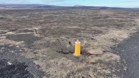 Islands-Dramatische-Küste-Wird-In-Dieser-Luftaufnahme-Eines-Farbenfrohen-Leuchtturms-Präsentiert,-Der-Auf-Einem-Schwarzen-Sandstrand-Inmitten-Von-Felsvorsprüngen-Und-Tosenden-Wellen-Thront