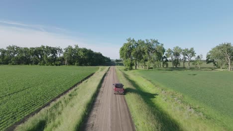 Rear-drone-view-of-a-truck-driving-down-country-road-at-rural-North-Dakota,-USA-at-afternoon