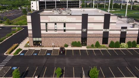 Aerial-dolly-to-side-sign-of-WhirlyBall-with-eat,-drink,-game-signs-on-edge-above-windows