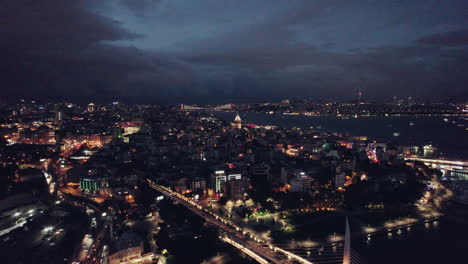 Wide-aerial-shot-of-Beyoglu-and-galata-tower-at-night-with-city-lights-and-a-stunning-cloudy-sky,-copy-space