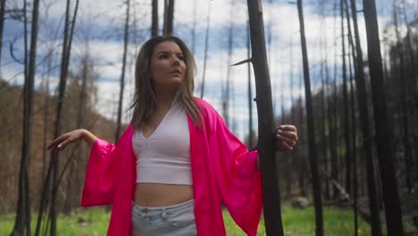 Girl-in-pink-wandering-through-bunrt-forest-trees