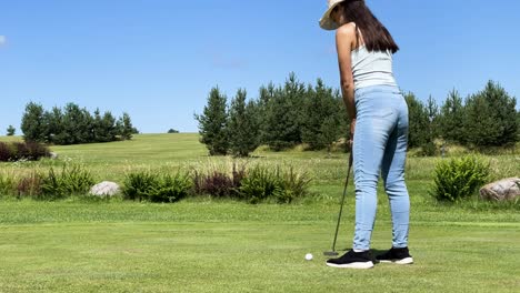 Female-golfer-use-putter-club-to-hit-ball-into-cup,-green-course-in-Latvia