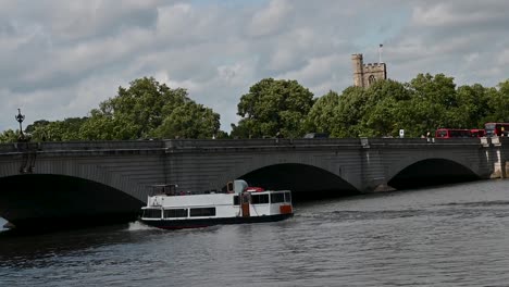 Barco-Blanco-Bajo-El-Puente-De-Putney-Junto-A-Todos-Los-Santos,-Fulham,-Londres,-Reino-Unido