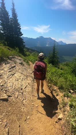 Vertikale-Ansicht,-Junge-Wanderin-Mit-Wanderstöcken-Auf-Einem-Wanderweg-In-Der-Wunderschönen-Landschaft-Des-Glacier-Nationalparks,-Montana,-USA