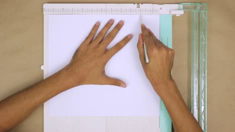 Hands-arranging-paper-on-a-folding-and-cutting-board-for-crafting-projects,-top-view