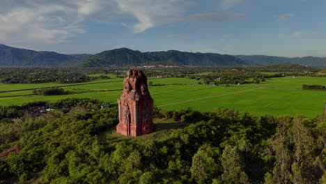 Phu-Loc-Champa-Temple,-aerial-fly-fly-past-revealing-lush-green-paddy-fields