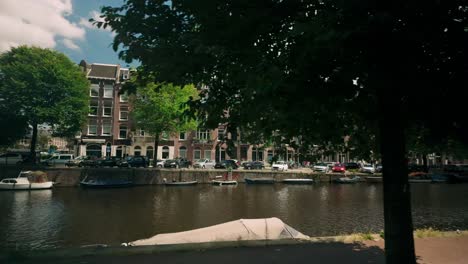 Canal-houses-and-water-during-a-sunny-summer-day-in-Amsterdam,-Netherlands