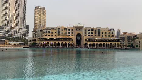 Pan-across-Burj-Khalifa-Lake,-Emaar-market-and-Dubai-city-skyline