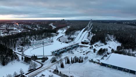 Drone-flying-around-the-ski-jump-towers,-winter-sunset-in-Salpausselka,-Lahti,-Finland