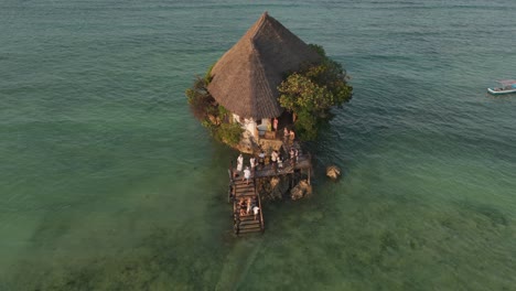 The-Rock-Restaurant-with-many-tourists-on-wooden-pier-on-the-sunset-during-high-tide