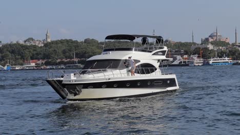 Eine-Gute-Sicht-Auf-Einen-Mann,-Der-Auf-Seiner-Yacht-Im-Eminonu-Pier-Mit-Den-Beiden-Berühmten-Moscheen-In-Istanbul-Segelt