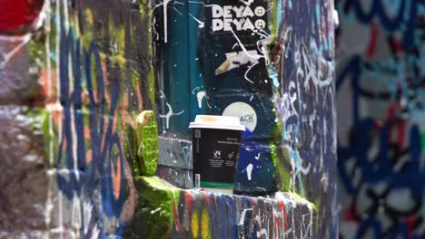 Die-Künstlerischen-Graffitiwände-Mit-Einer-Kaffeetasse-Auf-Dem-Fensterhocker,-Street-Art-Gasse,-Ausdruck-Von-Farben-Und-Konzept-Von-Vandalismus,-Nahaufnahme