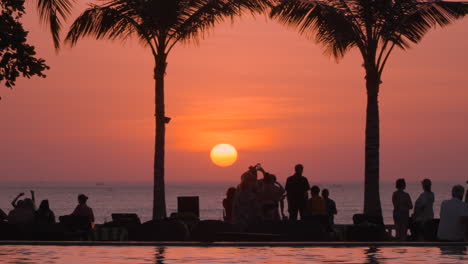 Turistas-Del-Complejo-Intercontinental-De-Bali-Frente-A-La-Playa-Viendo-La-Puesta-De-Sol-Sobre-El-Mar,-Indonesia