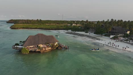 Shuttle-boat-brings-tourists-to-The-Rock-Restaurant-during-high-tide,-Zanzibar,-Tanzania