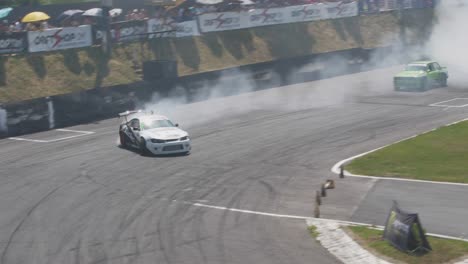 A-White-and-a-Green-race-cars-drifting-on-a-very-tight-curve-with-lots-of-smoke