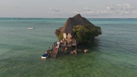 Shuttle-boat-brings-tourists-to-The-Rock-Restaurant-during-high-tide,-Zanzibar,-Tanzania