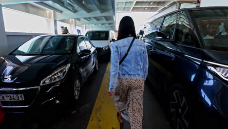 Woman-walks-between-vehicles-inside-ferry