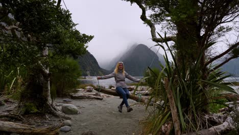 Lady-swinging-on-swing-made-from-a-branch-and-a-rope-on-the-bank-of-Milford-Sound