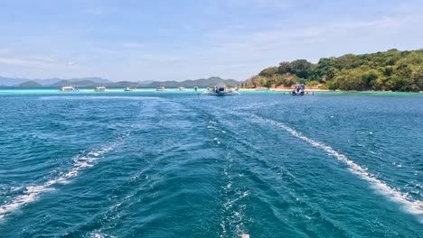 A-view-from-behind-a-sailing-boat-as-it-sails-from-Coron-to-El-Nido-in-Palawan,-Philippines