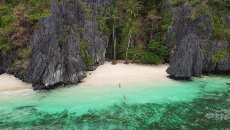 Vídeo-De-Dron-En-4k-De-Una-Pareja-Nadando-En-La-Playa-De-Entalula,-Una-Playa-De-Arena-Blanca-En-La-Isla-De-Entalula-Cerca-De-El-Nido-En-Palawan,-Filipinas