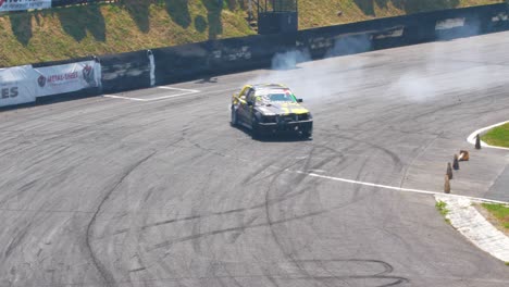 Yellow-race-car-drifting-on-a-very-tight-curve-with-lots-of-smoke-followed-by-a-drone